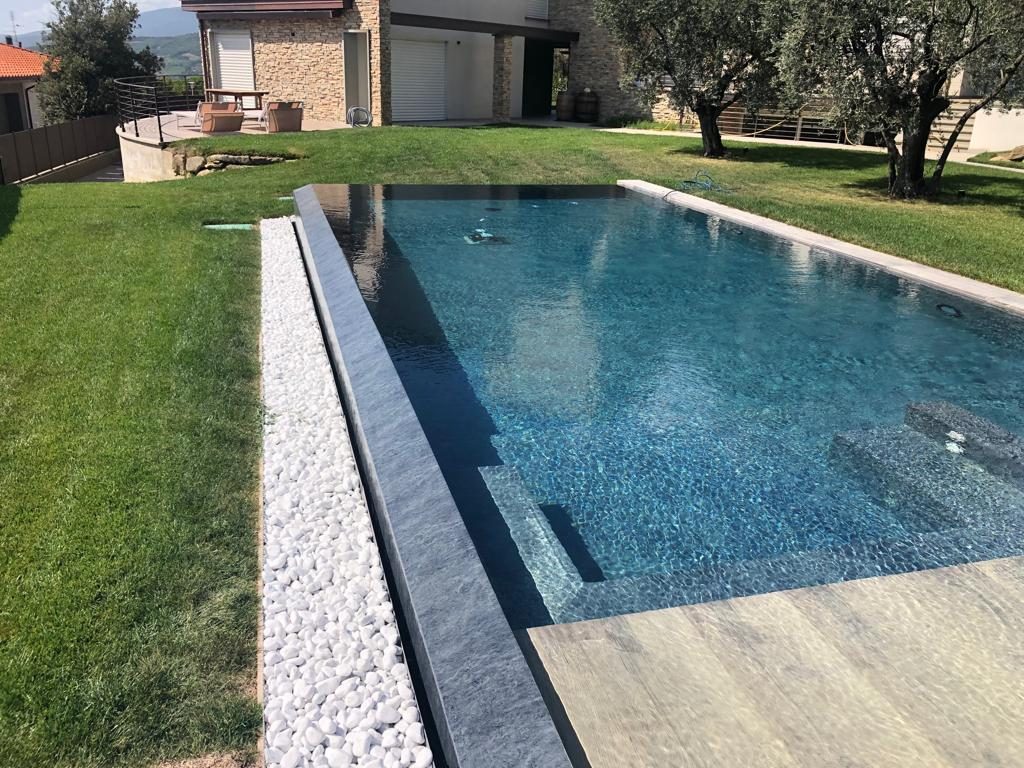 Piscina a sfioro con rivestimento scuro in un giardino