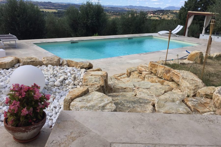 Piscina interrata tra rocce e ulivi con vista sulle colline umbre