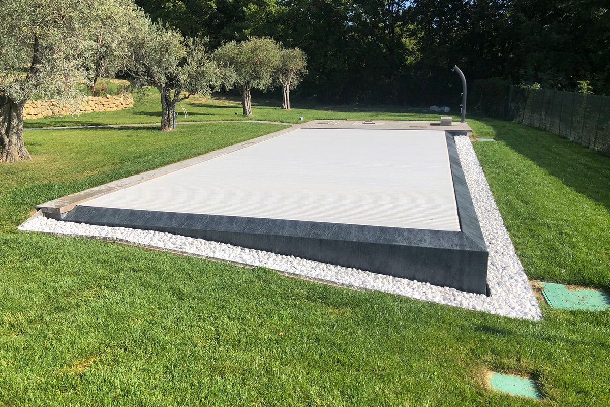 Piscina chiusa da una copertura a tapparella color sabbia tra gli ulivi