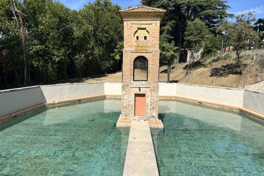 Torretta in mattoni al centro di una piscina, collegata al bordo da una passerella