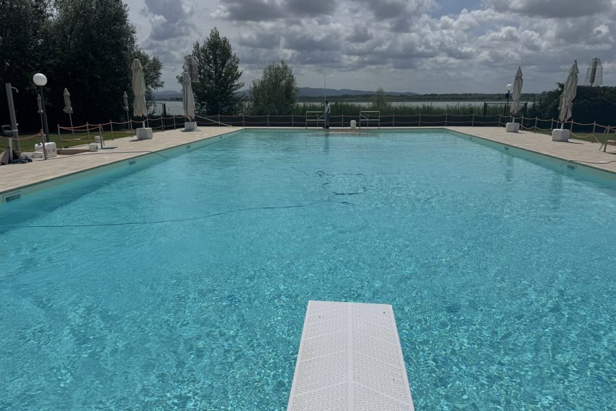 Grande piscina con trampolino e vista sul lago
