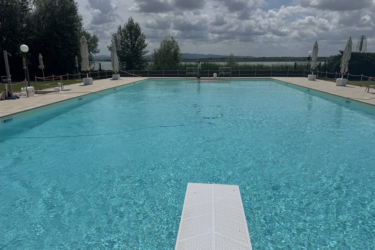 Grande piscina con trampolino e vista sul lago