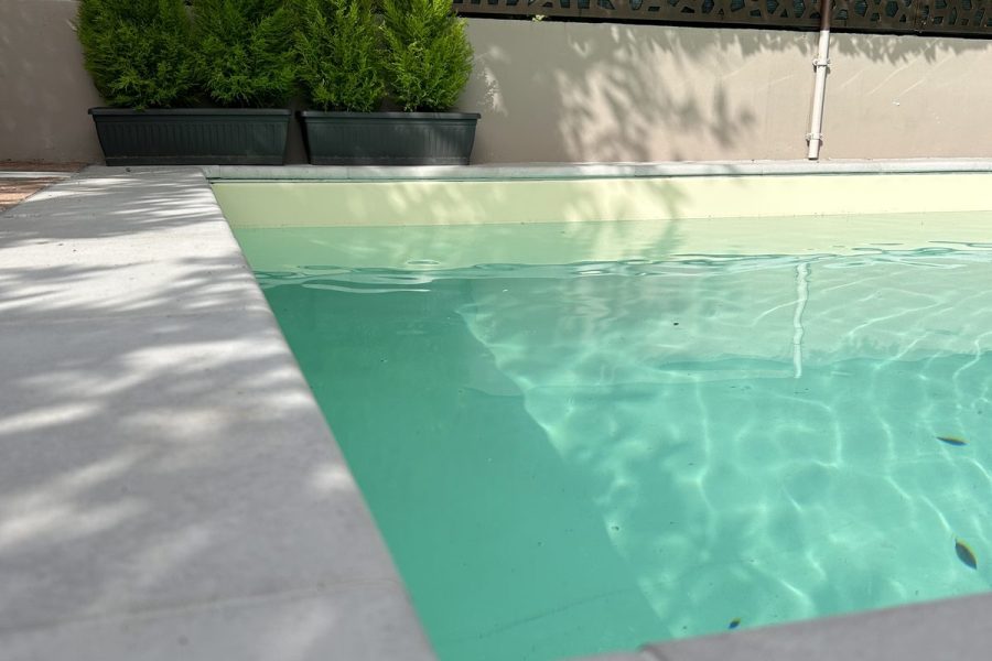 Angolo di una piscina con rivestimento chiaro e fioriere a Casaglia