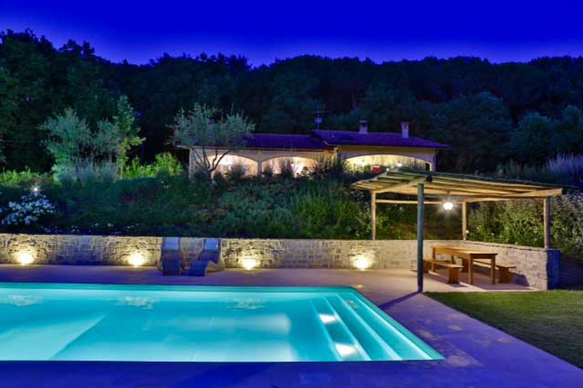 Piscina privata illuminata di sera nella campagna di Perugia