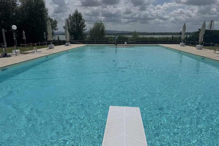 Grande piscina con trampolino e vista sul lago